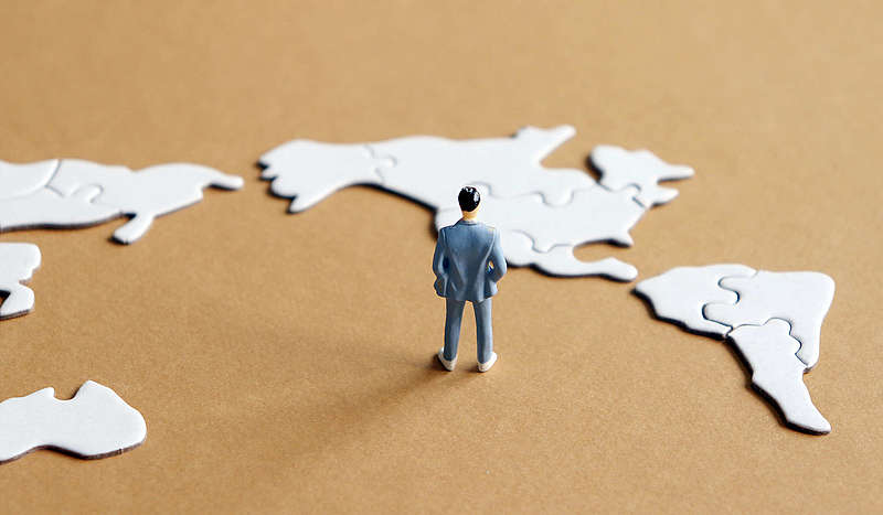 Among the world map puzzle the North American Map and standing miniature man.