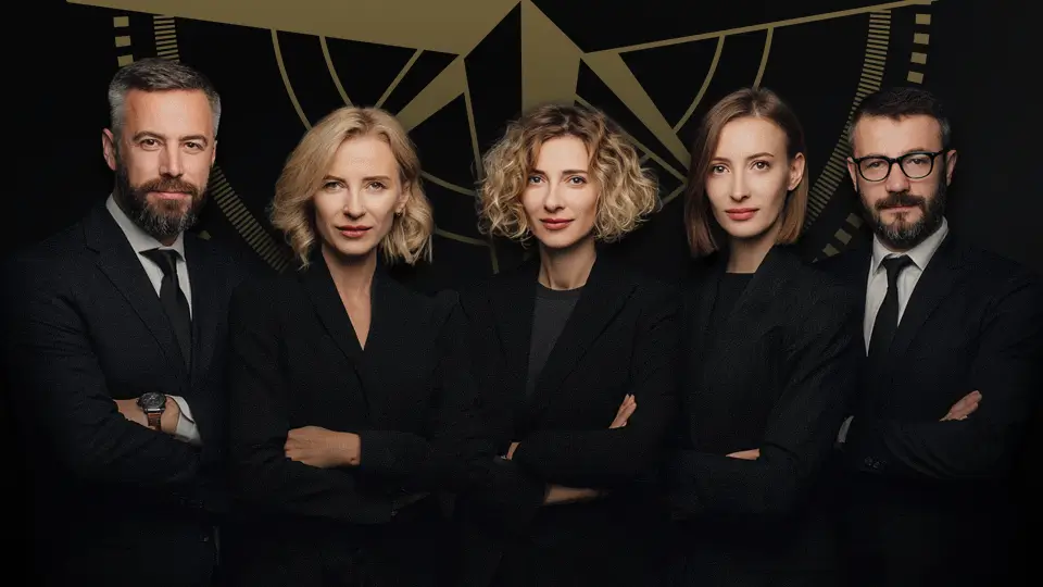 Cztery osoby w garniturach na ciemnym tle, uśmiechający się do kamery.