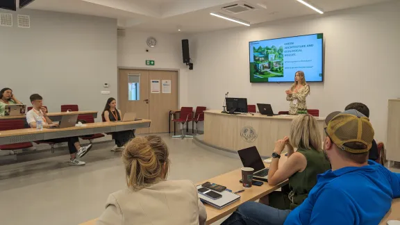 Student Darya Mialeshkina is standing and presenting in front of the audience
