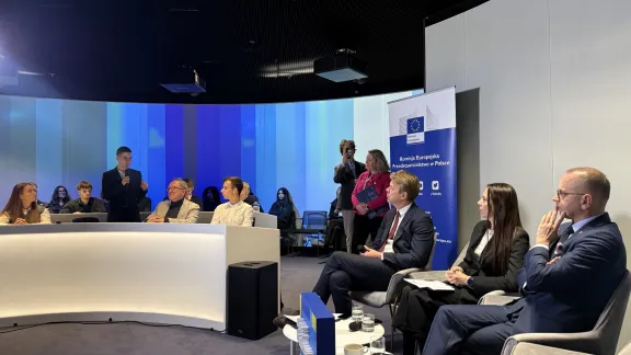 Uczestnicy spotkania w sali z roll-upem Przedstawicielstwa Komisji Europejskiej w Polsce