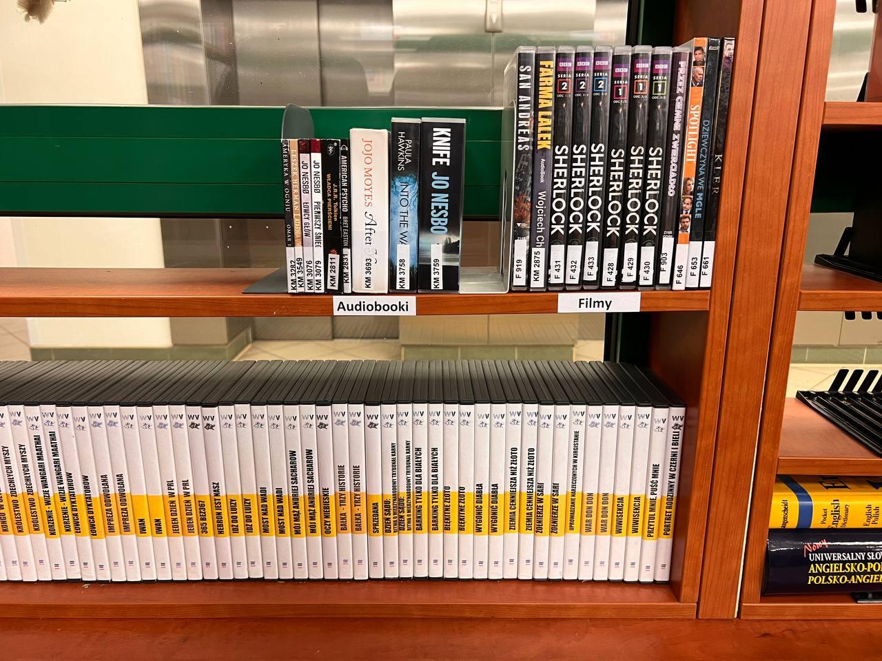 Półki z książkami na których znajdują się audiobooki i filmy DVD z napisami rozszerzonymi - zbiory Biblioteki Mokotowskiej.