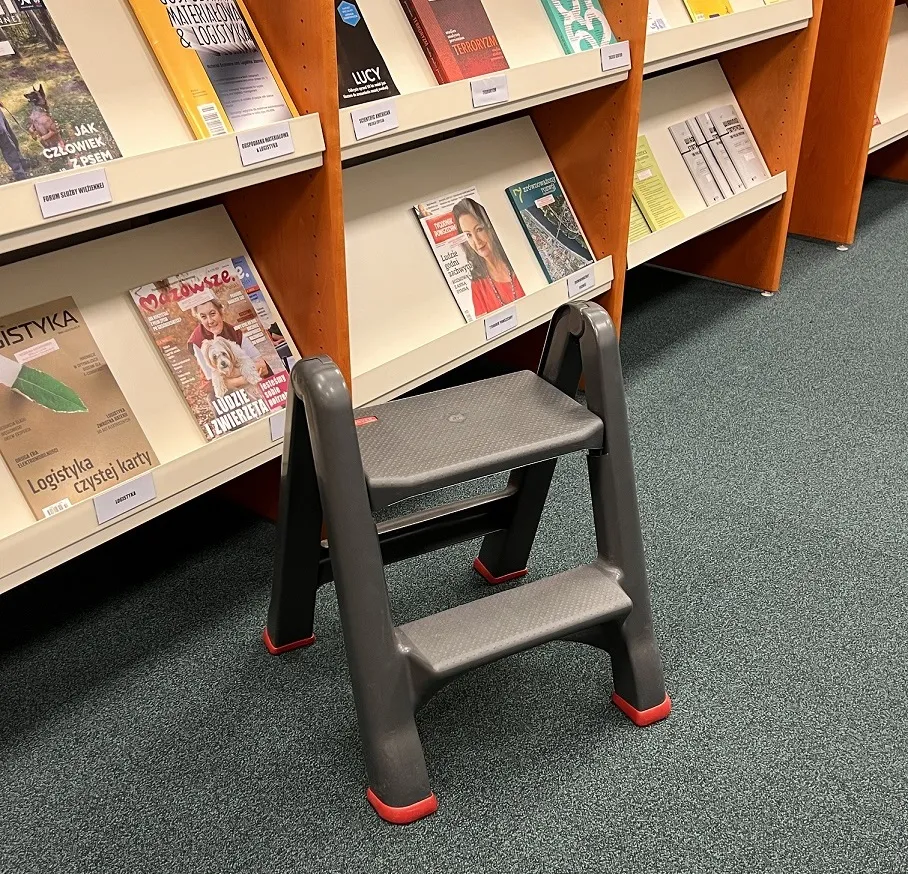 A gray plastic two-step ladder with red tips.