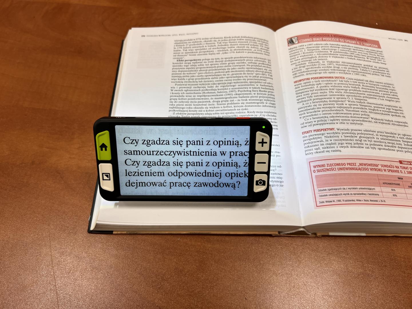 Lupa elektroniczna powiększająca fragment książki leżącej na biurku.