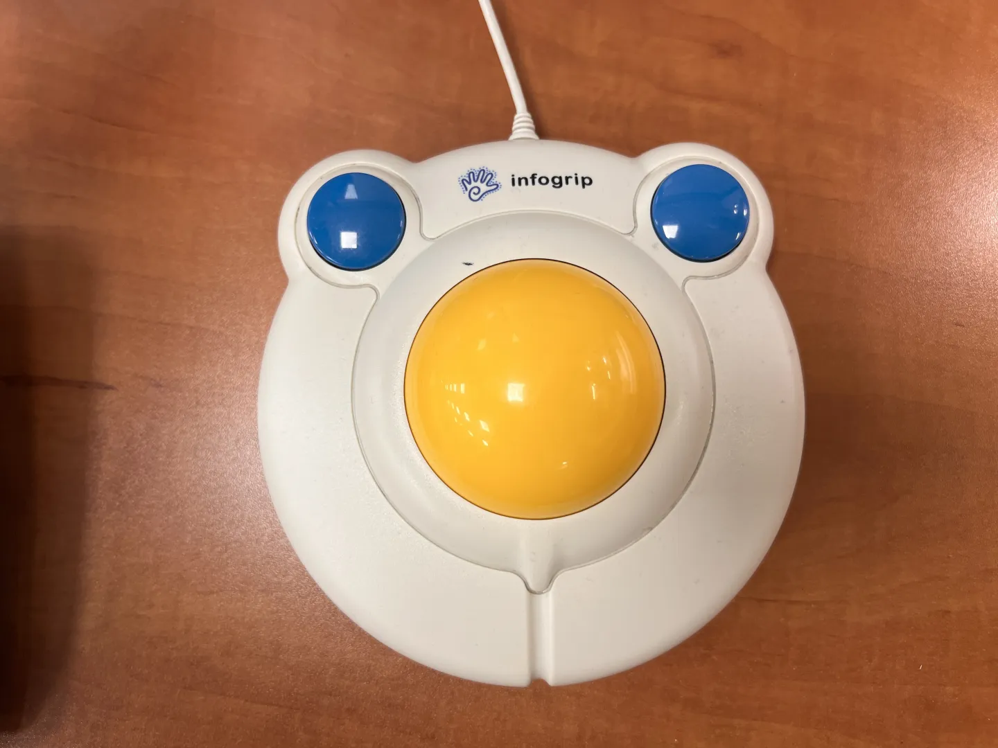 An enlarged white computer mouse with a yellow trackball, two large blue buttons, and the Infogrip company's name and logo.