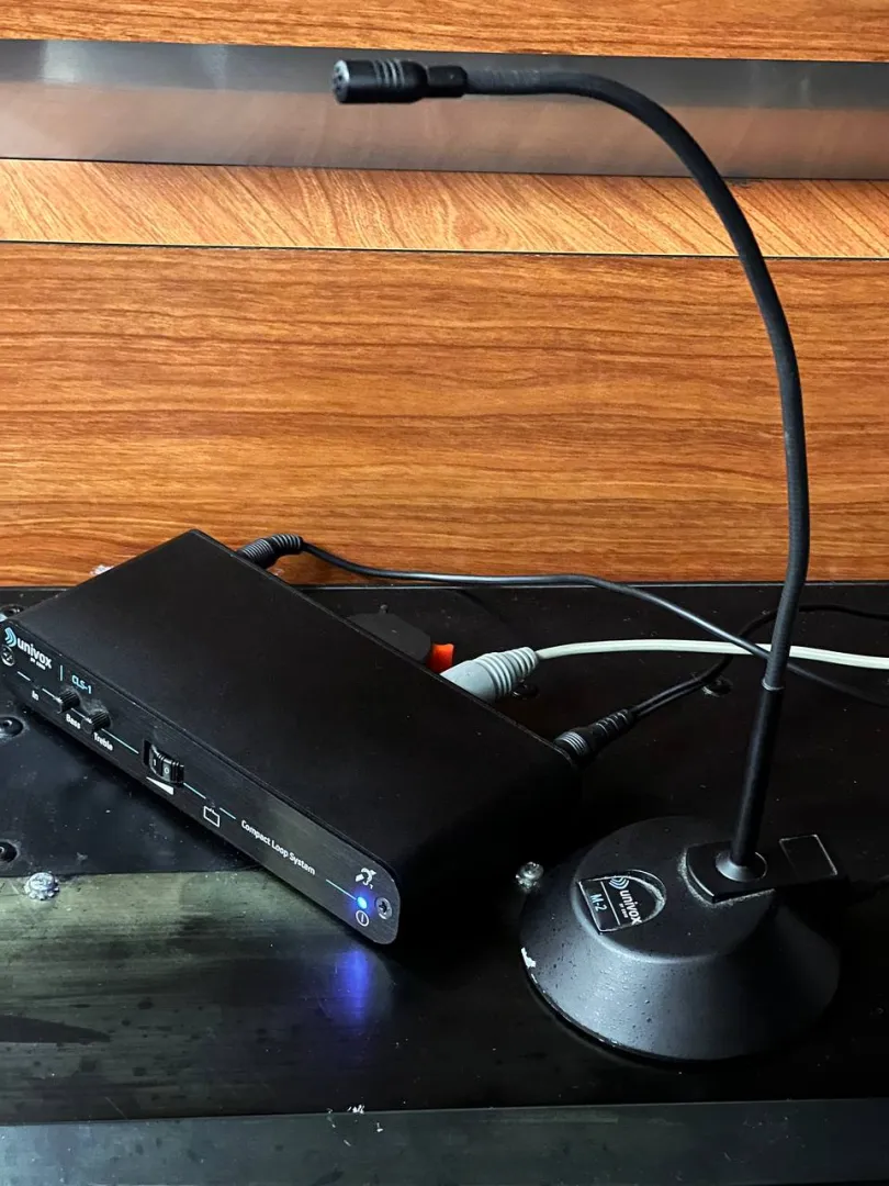 Induction loop amplifier with microphone lying on desk.