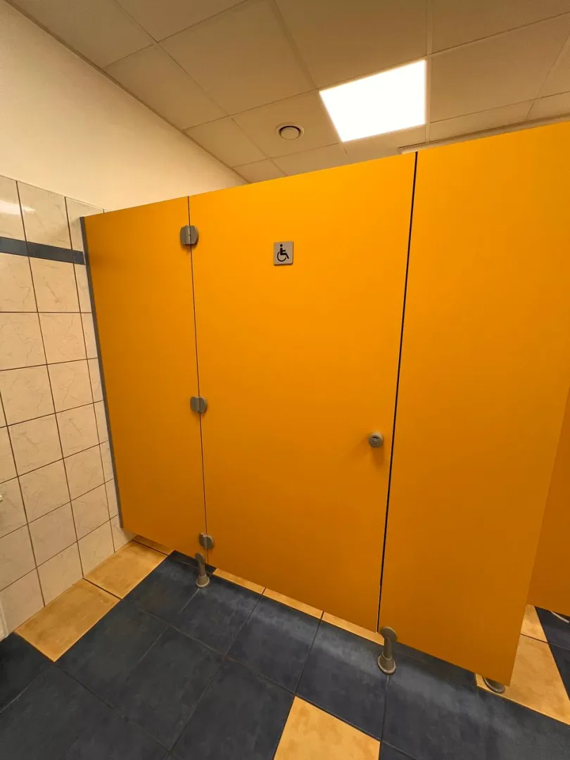 Bathroom with a wide yellow cabin and a sign of a person in a wheelchair on a gray background.