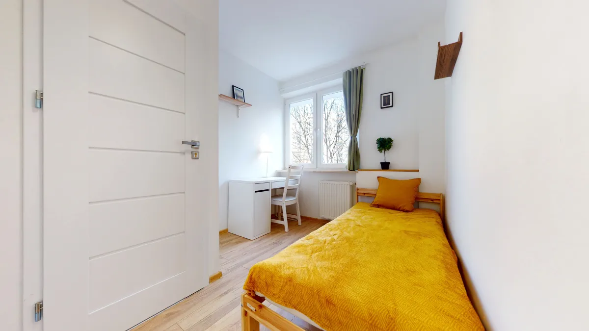 nearby dorm view of the room, white walls, bed covered with a yellow bedspread