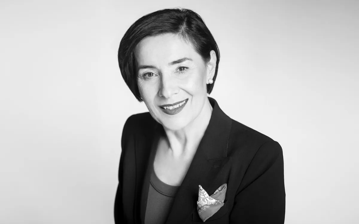 Czarnobiałem zdjęcie formalnie ubranej kobiety na jasnym tle
