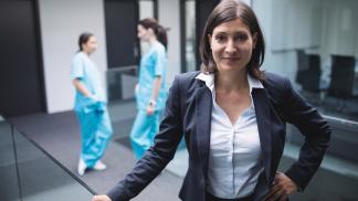 Kobieta zarządzająca szpitalem, w tle stoją dwie pielęgniarki