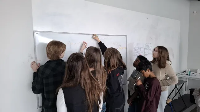 Grupa uczniów pracująca zespołowo przy białej tablicy podczas warsztatów prawnych z programu LEXLAB.