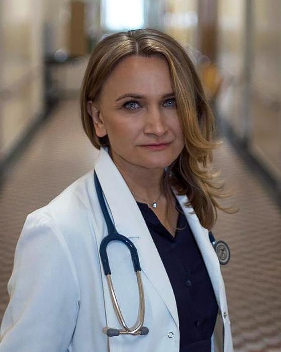 lekarka stojąca na szpitalnym korytarzu ze stetoskopem przewieszonym przez szyję - dr Olga Tronina - stomatologia łazarski